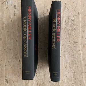 May include: Two black hardcover books by Henry Miller, "Tropic of Cancer" and "Black Spring", both published by Grove Press.