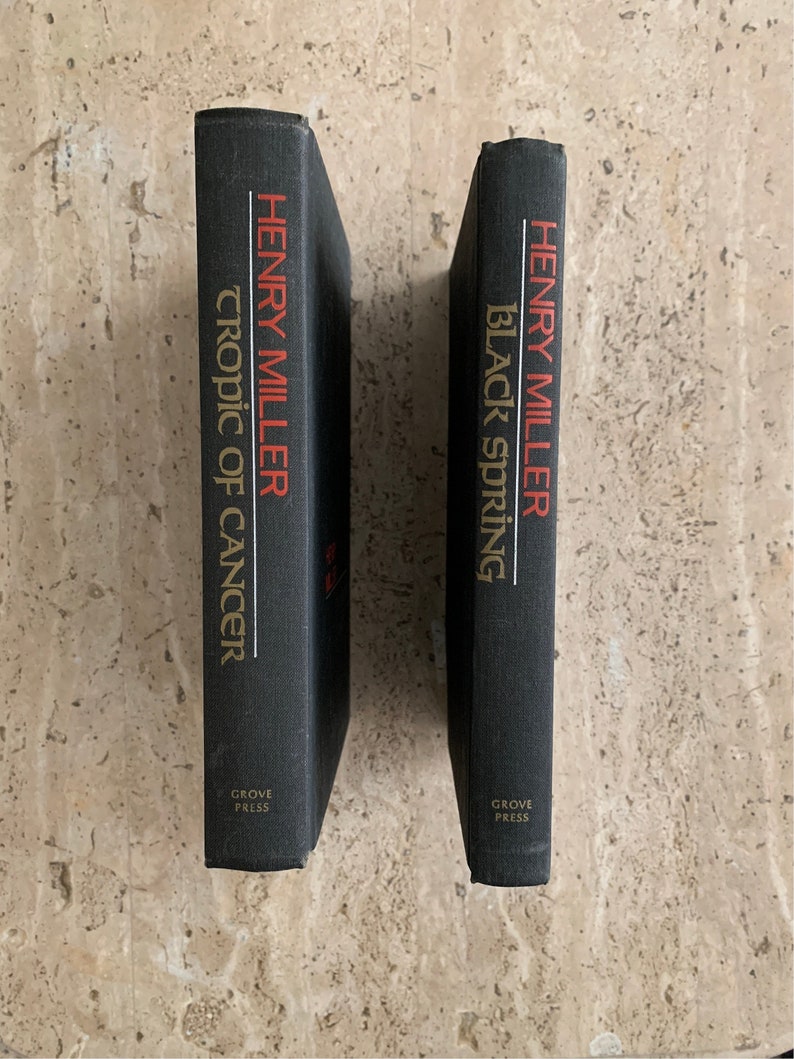 May include: Two black hardcover books by Henry Miller, "Tropic of Cancer" and "Black Spring", both published by Grove Press.