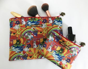 May include: Two colourful zippered pouches with a psychedelic rainbow and mushroom print. The larger pouch has the text "Stan & Ghyth" on it.