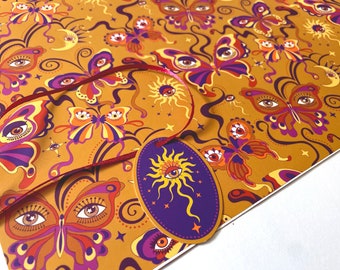 Peut inclure: Papier d'emballage doré avec un motif répétitif de papillons aux yeux, d'étoiles et de soleils. Le papier a une palette de couleurs violette et orange.
