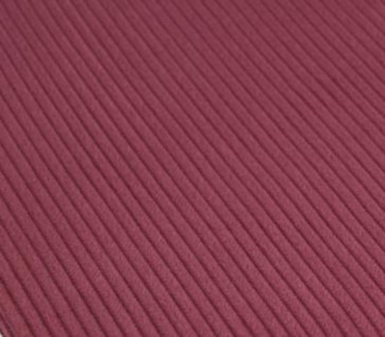 May include: A deep burgundy fabric featuring a consistent vertical ribbed texture. The material displays a series of parallel raised lines running diagonally across the surface, creating a uniform and tactile pattern throughout the entire textile.