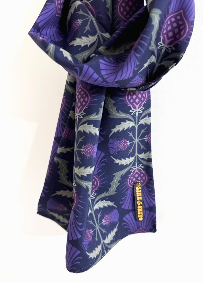 May include: A purple and green patterned silk scarf with a gold label that says "Stair & Co."