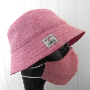 May include: A pink wool bucket hat with a red and white label that says "Hollywould" and "100% Australian Wool" in white text. The hat is paired with a pink wool face mask.