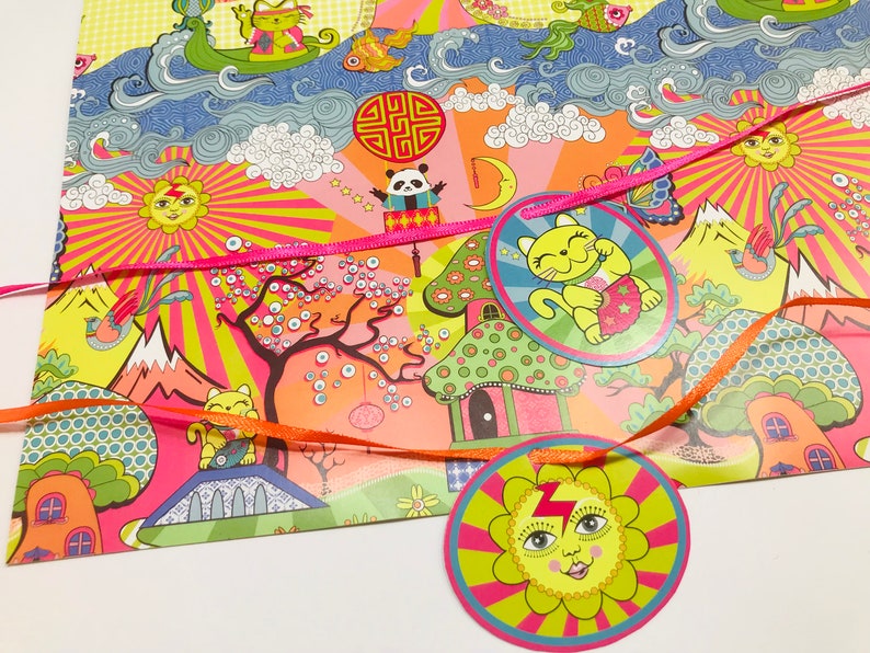 May include: A pink and yellow wrapping paper with a whimsical design featuring a cat, a panda, a sun, and a mushroom house. The paper is decorated with ribbons and stars.