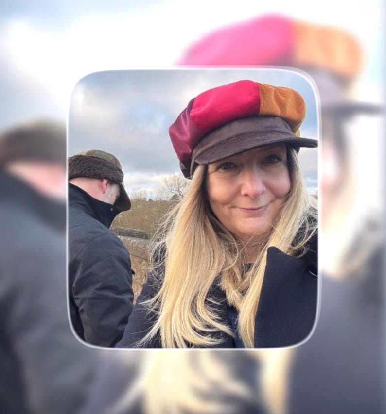 May include: A multi-colored newsboy cap featuring panels in shades of red, burgundy, and orange, complemented by a dark brown brim. The cap is constructed with a structured crown and a short, stiff visor, showcasing a vibrant patchwork design.