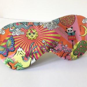 Könnte beinhalten: Eine farbenfrohe Schlafmaske mit einem Panda-, Sonnen-, Schmetterlings- und Pilzdesign. Die Maske ist aus weichem Stoff gefertigt und hat ein elastisches Band.