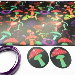 Puede incluir: Papel de regalo negro con un patr&oacute;n de setas colorido. Tambi&eacute;n se ven dos etiquetas de regalo ovaladas negras con un dise&ntilde;o de seta roja y una cinta morada.