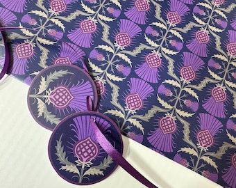 May include: Purple and gold patterned gift wrap with a repeating thistle design. Two round gift tags with a purple thistle design and a purple ribbon.