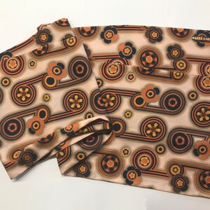 Pu&ograve; includere: Set di quattro tovaglioli in tessuto beige con un motivo geometrico retr&ograve; in tonalit&agrave; di marrone, arancio e giallo. Il motivo presenta cerchi, linee e fiori stilizzati.