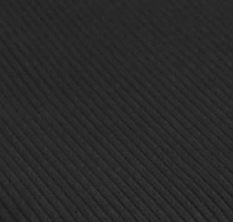 May include: A solid black fabric featuring a distinct corduroy texture with parallel vertical ridges running diagonally across the surface. The material has a matte finish and a consistent dark tone throughout the entire visible area.