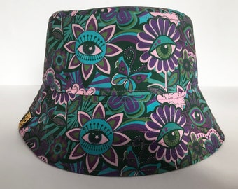 May include: A green, purple, and blue bucket hat with a psychedelic floral pattern featuring eyes and butterflies.