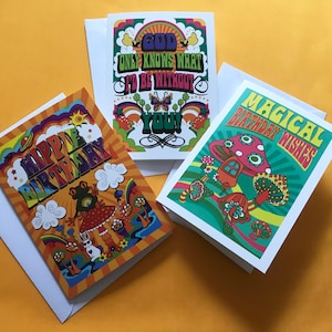 Op de afbeelding: Drie kleurrijke wenskaarten met psychedelische ontwerpen. De eerste kaart heeft een regenboogachtergrond met de tekst "God Only Knows What I'd Be Without You". De tweede kaart heeft een groene achtergrond met de tekst "Magical Birthday Wishes". De derde kaart heeft een oranje achtergrond met de tekst "Happy Birthday".