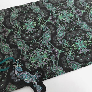 K&ouml;nnte beinhalten: Schwarzes Geschenkpapier mit einem sich wiederholenden Muster aus gr&uuml;nen und violetten Pfauen und floralen Designs.