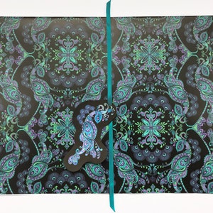 K&ouml;nnte beinhalten: Schwarzes Geschenkpapier mit einem t&uuml;rkisfarbenen Paisley-Muster und einem Pfauen-Design. Das Papier ist mit einem t&uuml;rkisfarbenen Band gebunden.