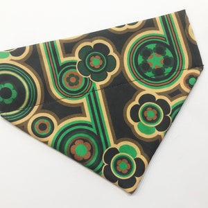 May include: A green, brown and black patterned dog bandana with a retro design. The bandana features a repeating pattern of circles, swirls and flowers.