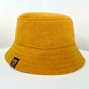 May include: A mustard yellow bucket hat with a black label that says "Stan & Green".