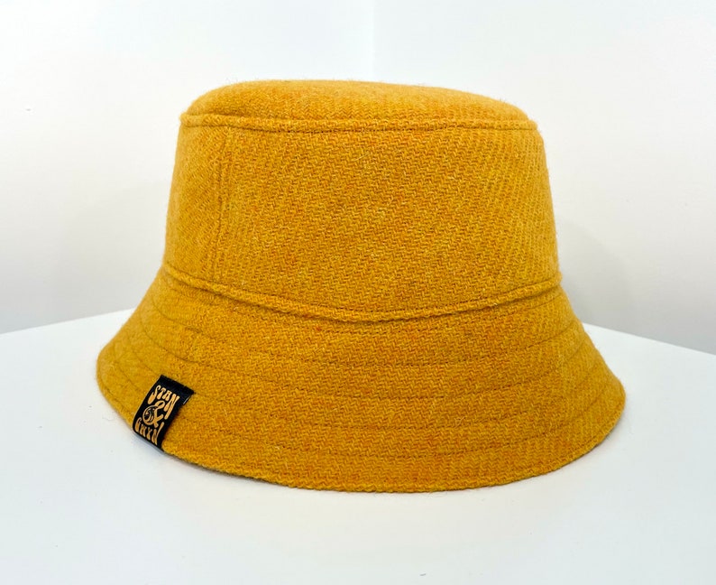 May include: A mustard yellow bucket hat with a black label that says "Stan & Green".