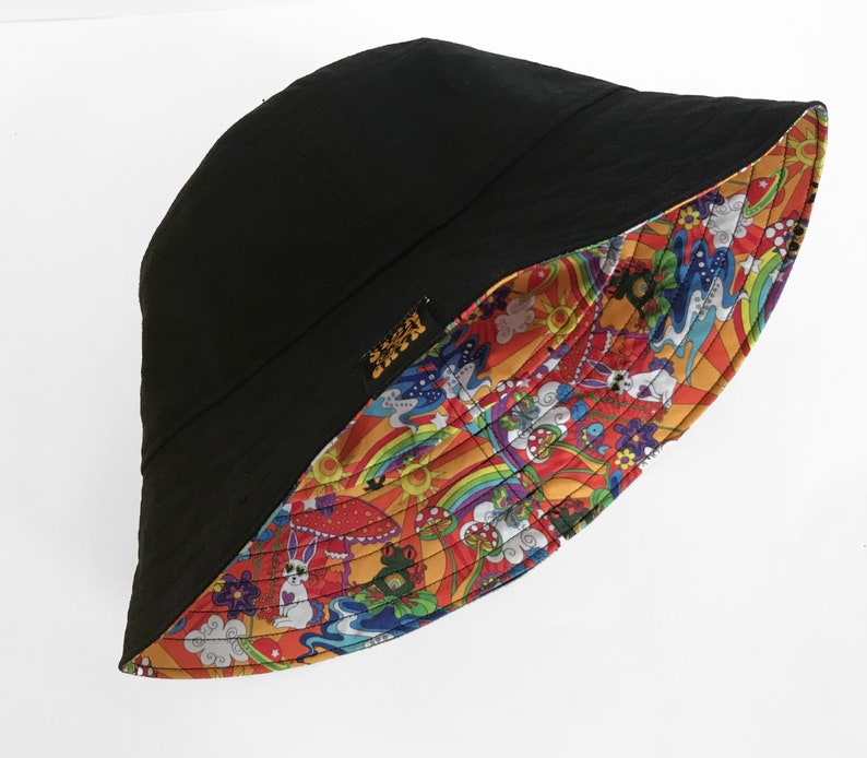 May include: A black bucket hat with a colorful psychedelic print on the inside. The print features rainbows, mushrooms, clouds, and other whimsical designs.
