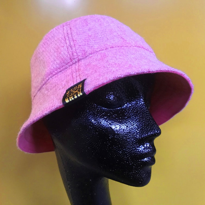 May include: A pink bucket hat with a gold logo that says "S.O.N.N.Y." on the side.