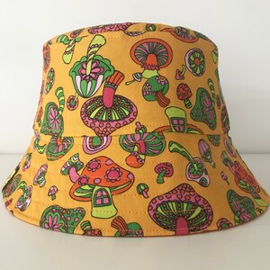 May include: A yellow bucket hat with a psychedelic mushroom print in shades of pink, green, orange, and brown.