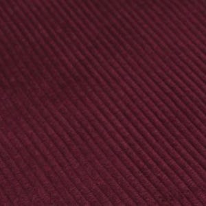 May include: A deep burgundy fabric featuring a distinct corduroy texture with parallel vertical ridges running diagonally across the frame. The material displays a consistent dark red hue with subtle shadows between the raised lines of the fabric.