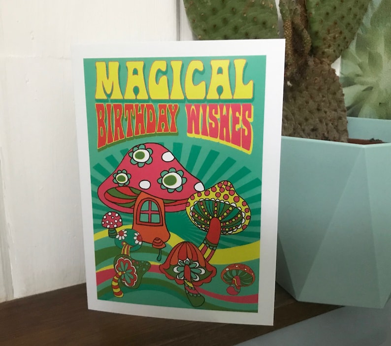 Op de afbeelding: Een kaart met een psychedelisch ontwerp met paddenstoelen en de tekst "Magical Birthday Wishes".