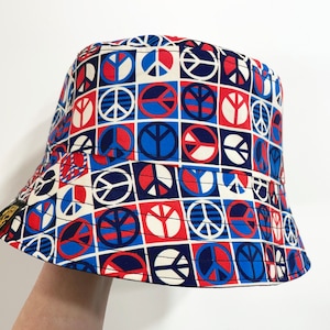 May include: A white bucket hat with a red, blue, and white peace sign pattern.