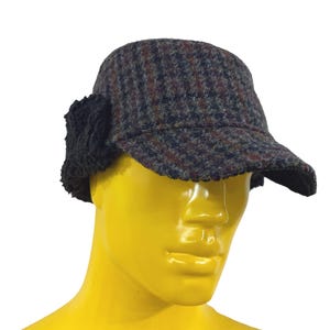 May include: A tweed hat with ear flaps. The hat is primarily dark blue with red and brown flecks. The ear flaps are black and fuzzy. The hat has a short brim.