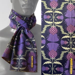 May include: A dark blue silk scarf with a repeating pattern of purple and pink thistles. The scarf has a gold label that says "Silk & Thistle".