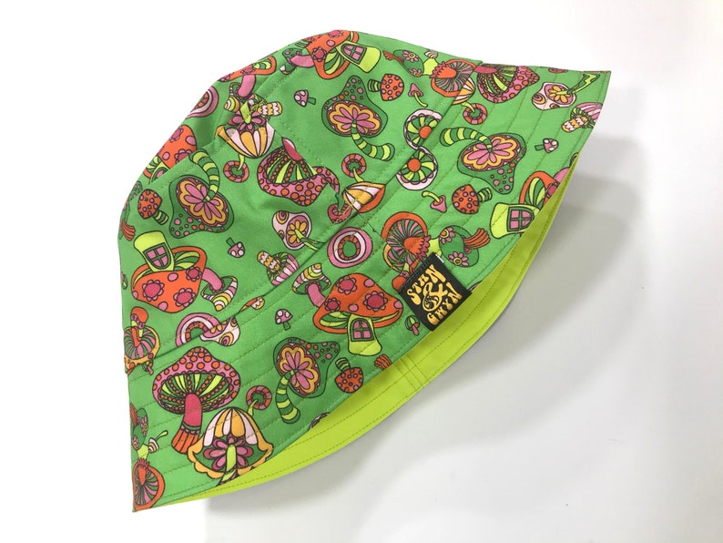 May include: Green bucket hat with a psychedelic mushroom print and the text "Seen & Green" in black.