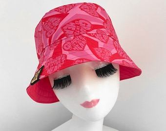 May include: Pink bucket hat with a heart pattern and the text "Groove is in the heart" repeated on the fabric.