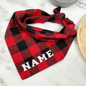 May include: Red and black plaid bandana with the word "NAME" in white lettering.
