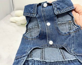 May include: A blue denim dog vest with a button closure and two pockets. The vest has a cut-out for the dog's tail.