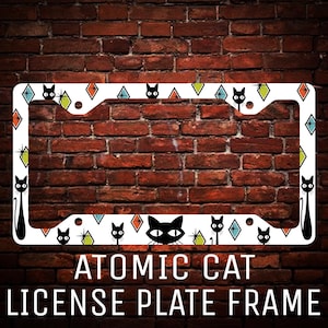 May include: White metal license plate frame with a black cat and geometric design. The frame has the text "Atomic Cat License Plate Frame".