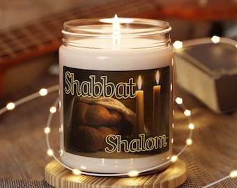 May include: A lit candle in a glass jar with a label that reads "Shabbat Shalom." The label features an image of challah bread and lit candles. The candle sits on a wooden coaster, surrounded by string lights.