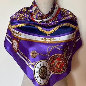 May include: A purple silk scarf with a gold and white pattern of chains, pocket watches, and Roman numerals. The scarf is folded and displayed on a mannequin.
