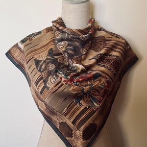 Peut inclure: Un foulard en soie brun et vert avec un motif paisley et un motif floral. Le foulard a une bordure vert foncé.