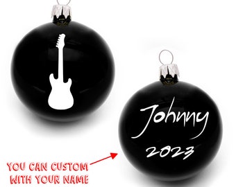 May include: Black Christmas ornament with a white electric guitar silhouette. Another ornament is black with white text that says "Johnny 2023".
