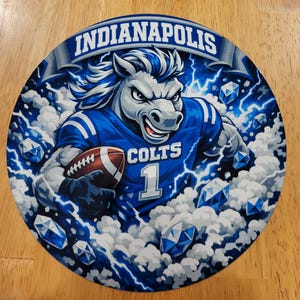 May include: Circular Indianapolis Colts graphic featuring a stylized horse wearing a blue jersey with the number 1 and holding a football. The design includes the word "Indianapolis" and "Colts" in white, with blue lightning and diamond shapes.