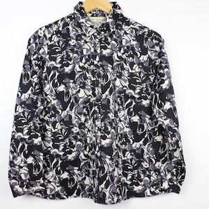 May include: A long-sleeved button-up shirt with a black and white abstract floral print.