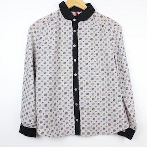 May include: A white long-sleeved button-down shirt with a black collar and a small geometric pattern. The shirt has a black button placket and black cuffs.