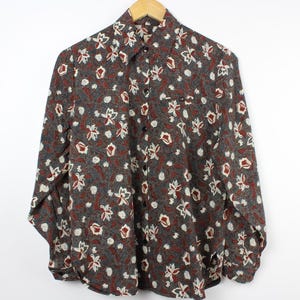 May include: A long-sleeved button-down shirt with a floral print in shades of brown, red, and white.