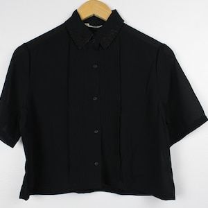 May include: A black short-sleeved button-up shirt with a decorative black collar.