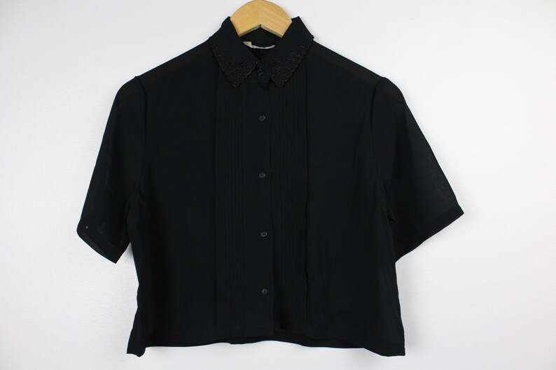 May include: A black short-sleeved button-up shirt with a decorative black collar.