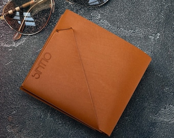May include: A brown leather wallet with the word "Ollys" embossed on the front. The wallet is folded in half and has a triangular flap.