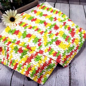 May include: A crocheted dishcloth in a chevron pattern with white, yellow, green, and orange yarn.