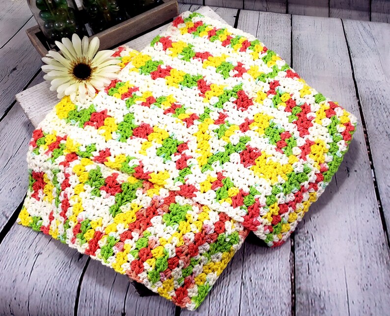 May include: A crocheted dishcloth in a chevron pattern with white, yellow, green, and orange yarn.