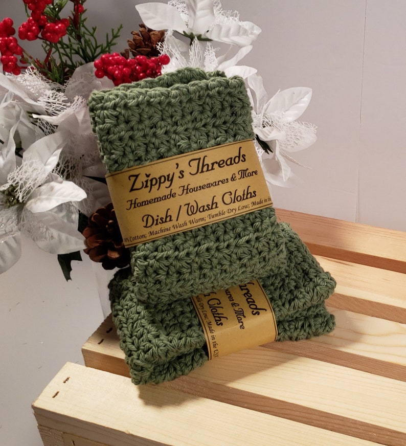 May include: Two green crocheted dishcloths with a brown label that reads "Zippy's Threads Homemade Housewares & More Dish/Wash Cloths Cotton; Machine Wash Warm; Tumble Dry Low; Made in the USA"