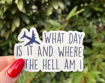 May include: White sticker with a blue airplane graphic and the text "What day is it and where the hell am I".