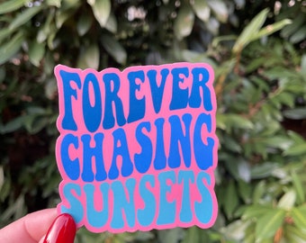 May include: Pink sticker with blue text that reads "FOREVER CHASING SUNSETS" in a retro font.